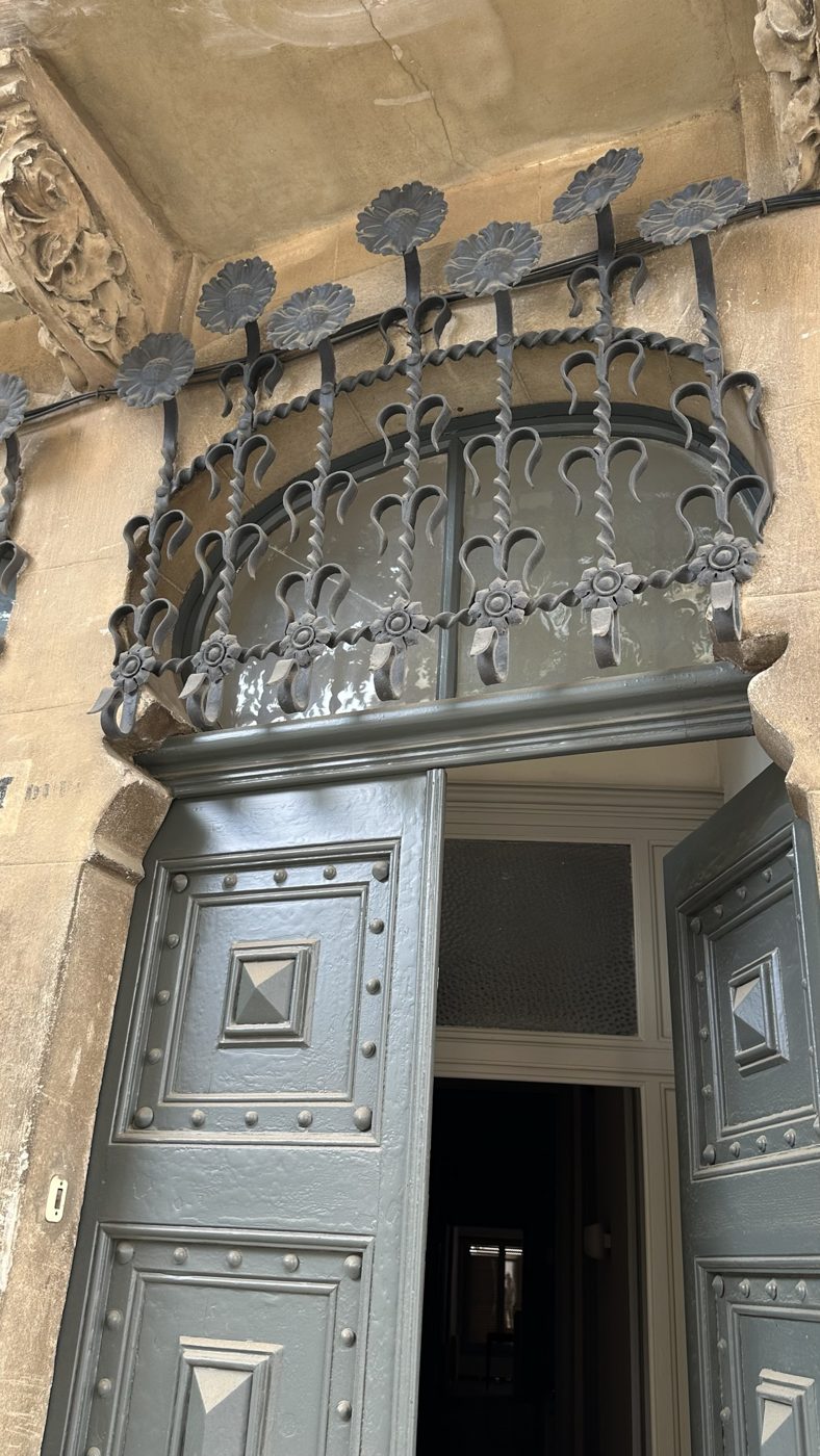 Reixa de ferro forjat amb set gira-sols a la porta de Casa Esteva